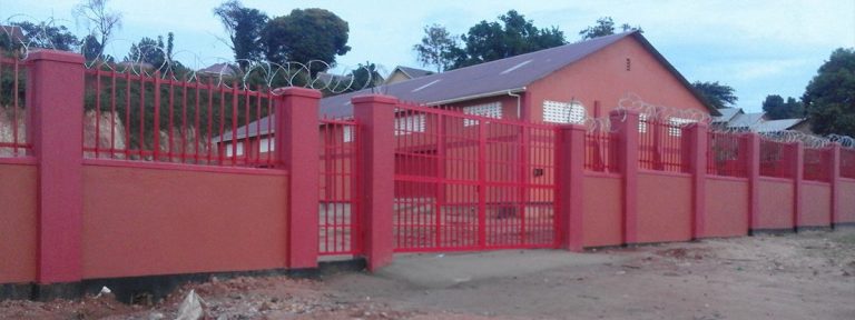 Red perimeter fence and gate around a completed building
