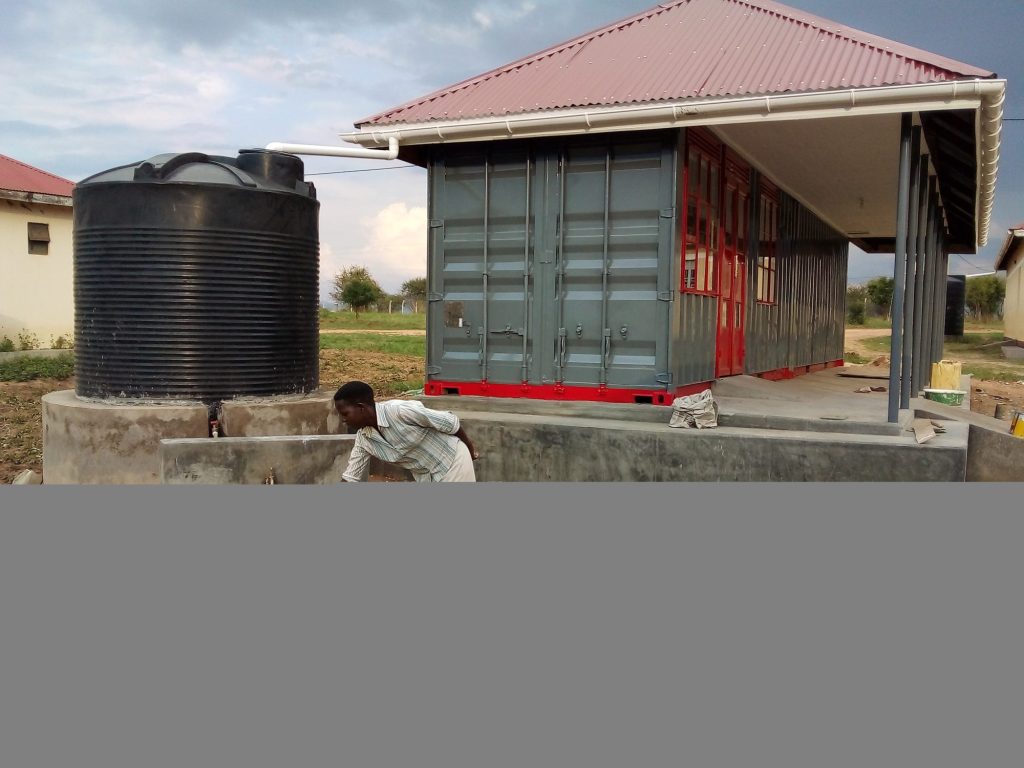 Water tank on a raised stand beside a completed building